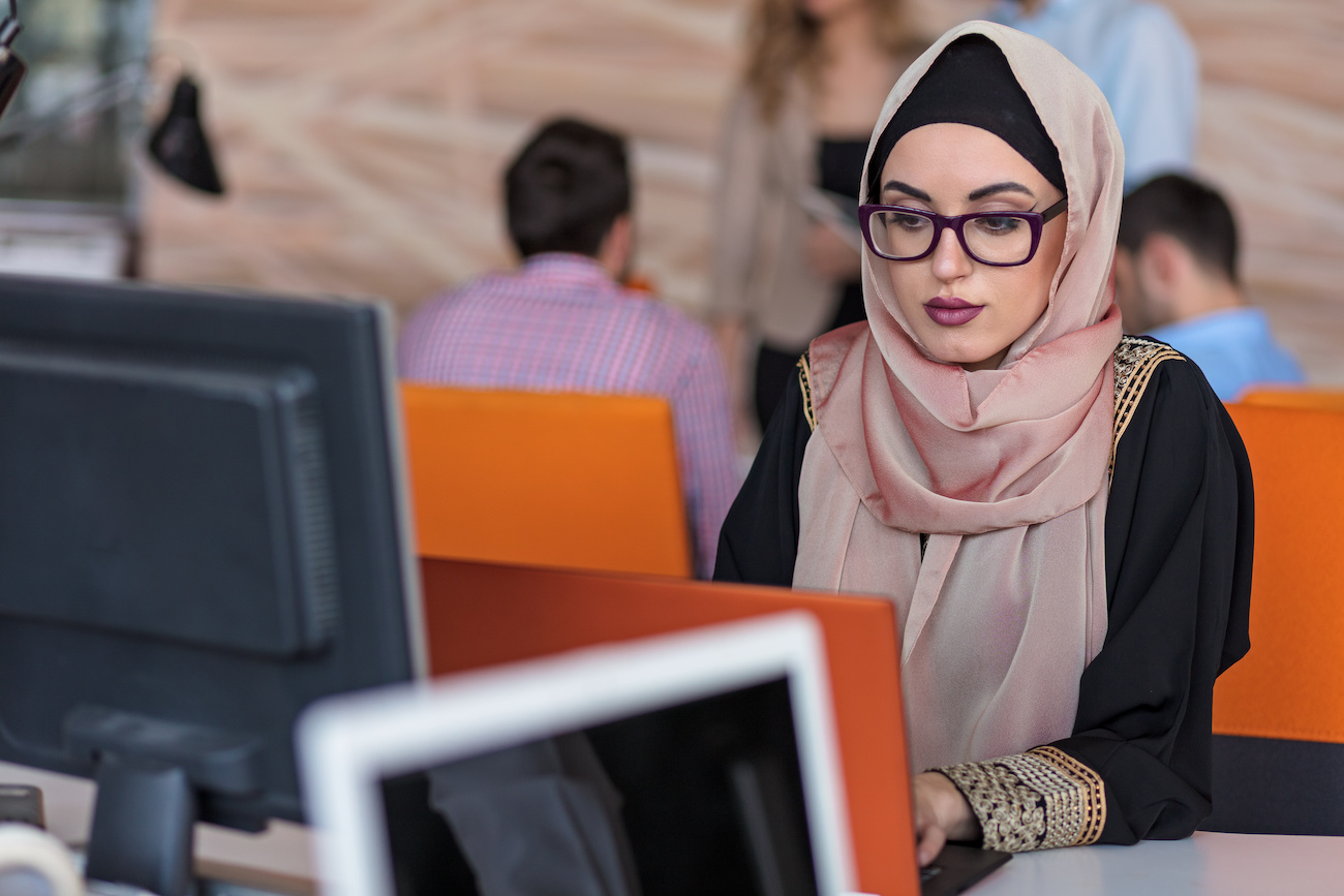 donna iraniana con velo lavora davanti al computer