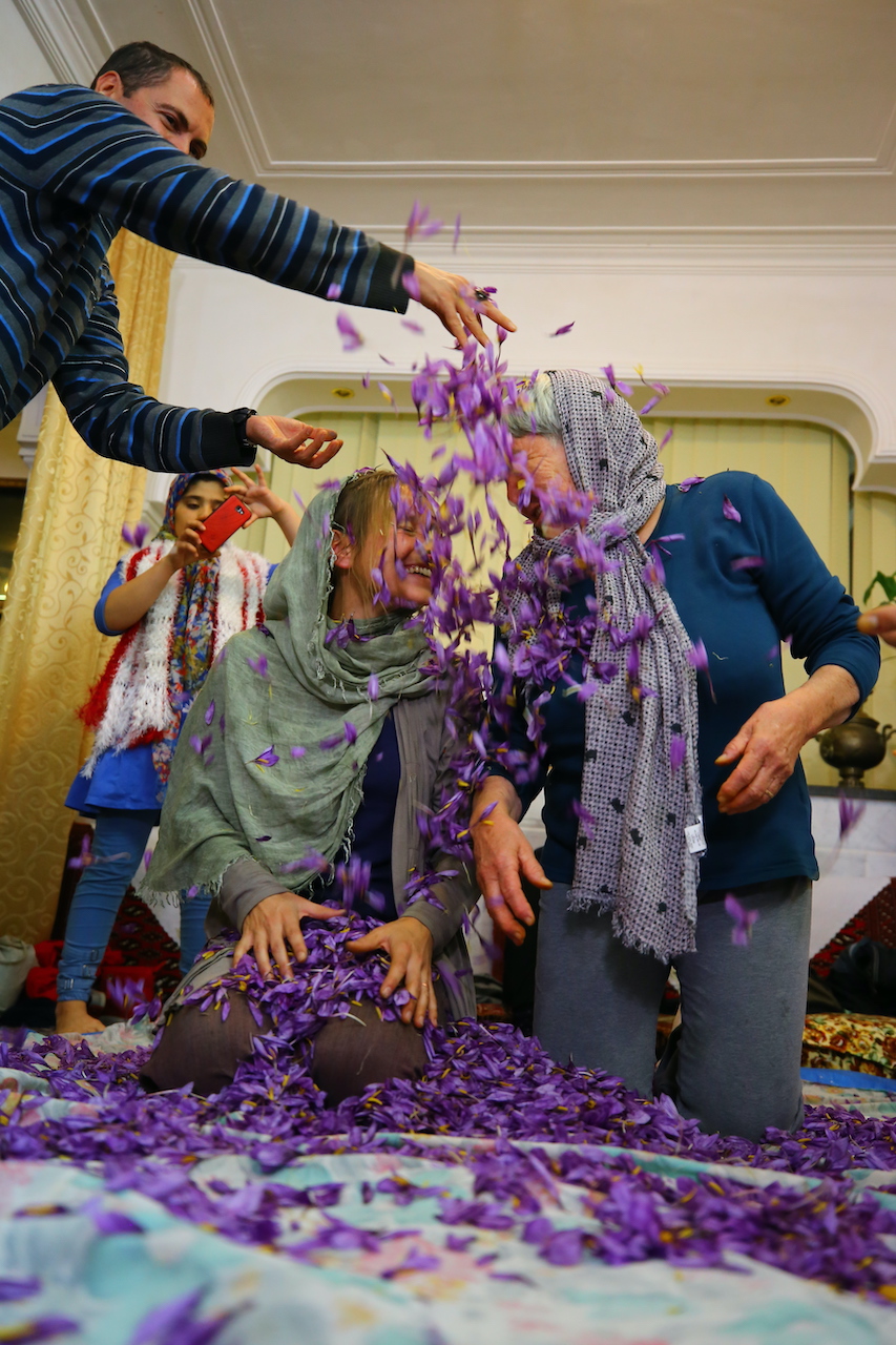 due donne ridono mentre gli viene gettata una pioggia di petali di zafferano durante il viaggio in Iran del 2019